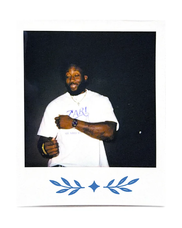 A member in the Zari tee against a dark wall at night.