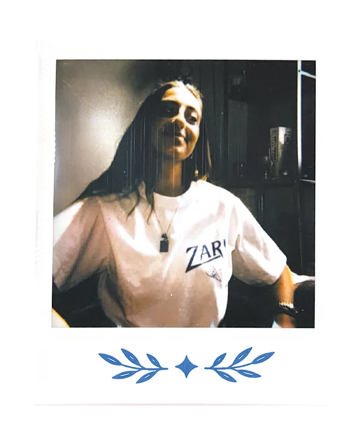 A member indoors, leaning back, in the Zari tee.