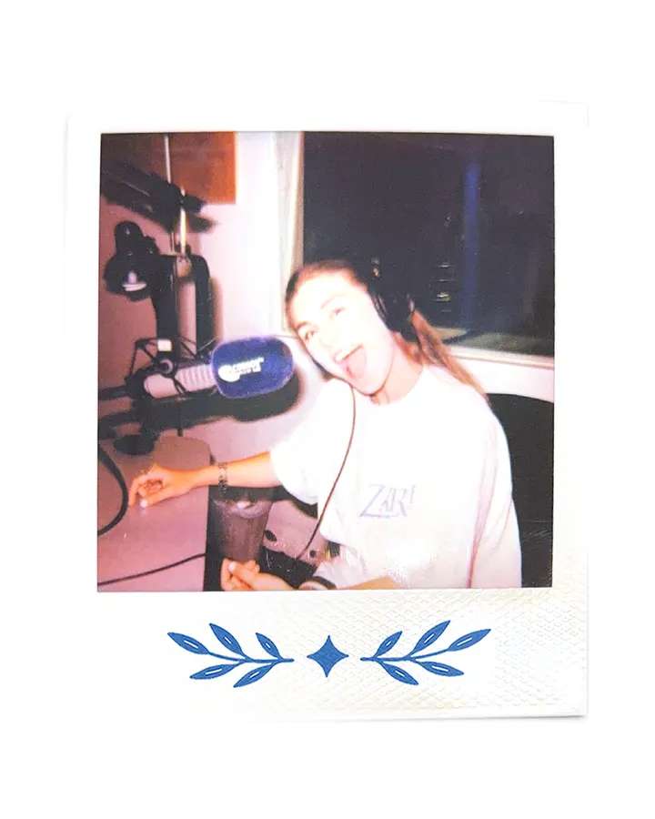 A member in headphones at the microphone, in the Zari tee.